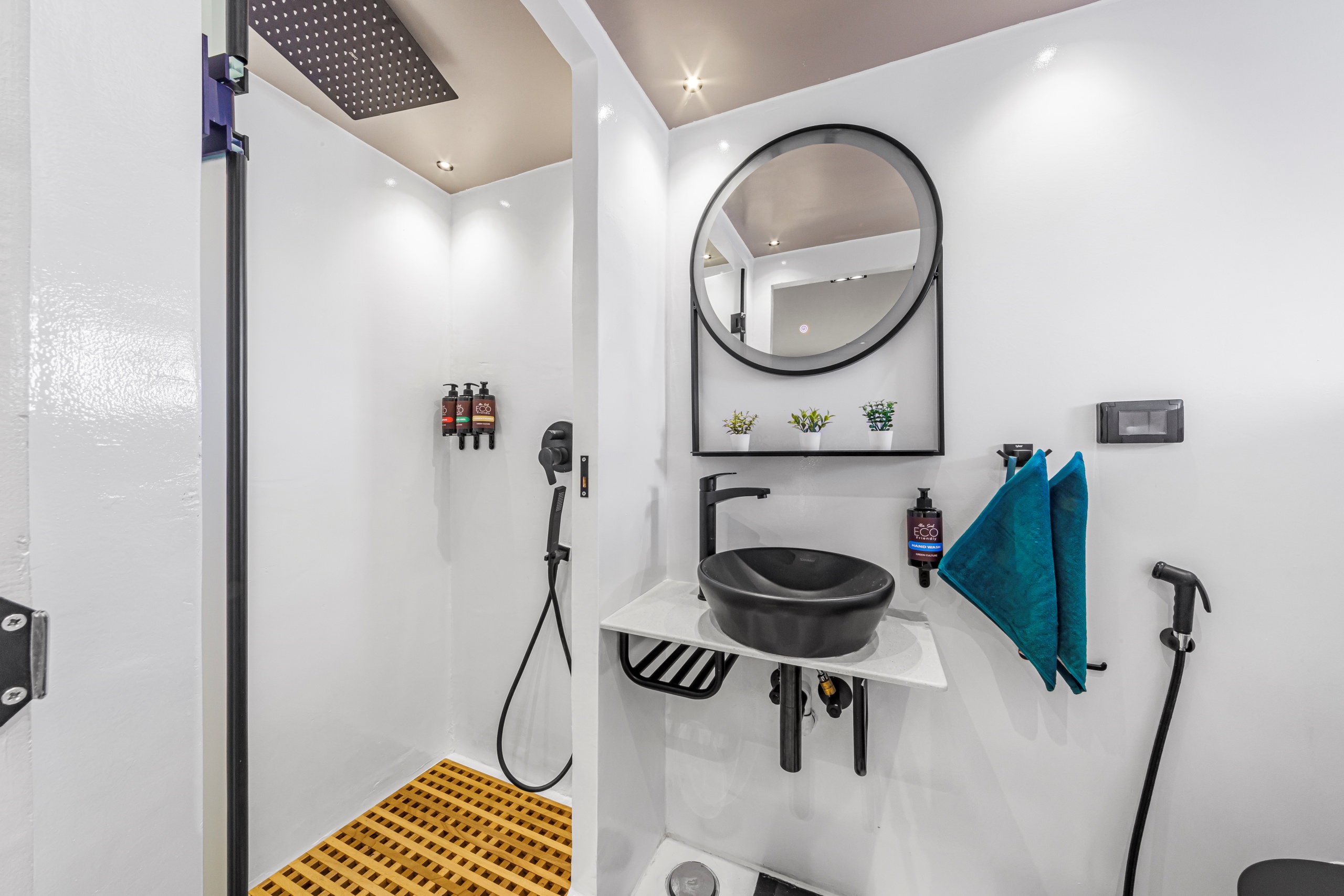 Ein Badbeispiel mit weißen Wänden und schwarzem Waschtisch, Spiegel, schöner Duschbereich